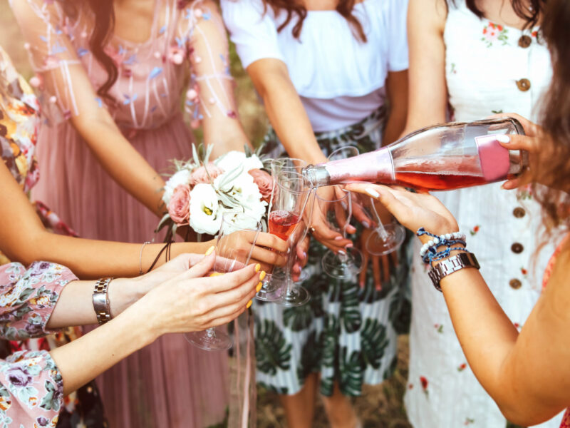 Champagne with glasses in girls hands at hen party outdoor